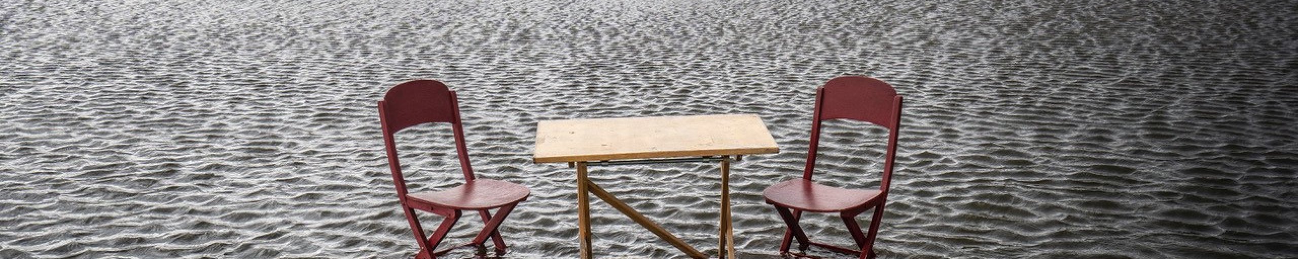 Foto van twee stoelen en een tafel in een ondergelopen polder